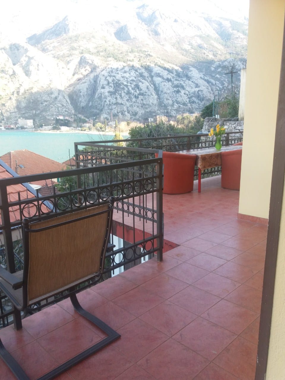 Terrasse mit Möbeln und Blick auf die Bucht von Kotor und die Berge im Haus, Muo, Montenegro. Fliesenboden und schmiedeeiserne Geländer.