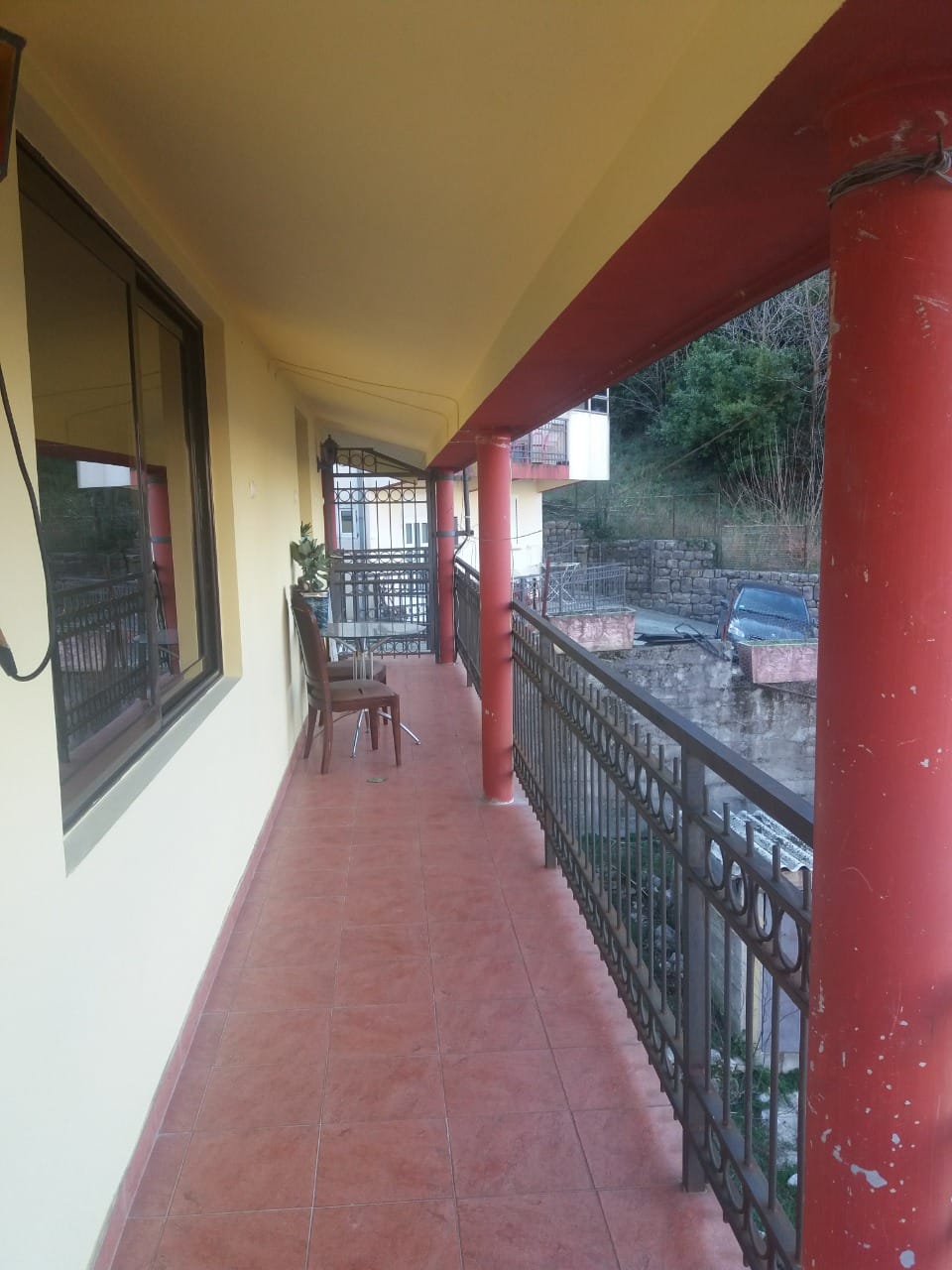 Geräumiger Balkon mit roten Säulen und Möbeln im Haus, Stadt Muo, Montenegro: Blick auf die Terrasse und den Garten.