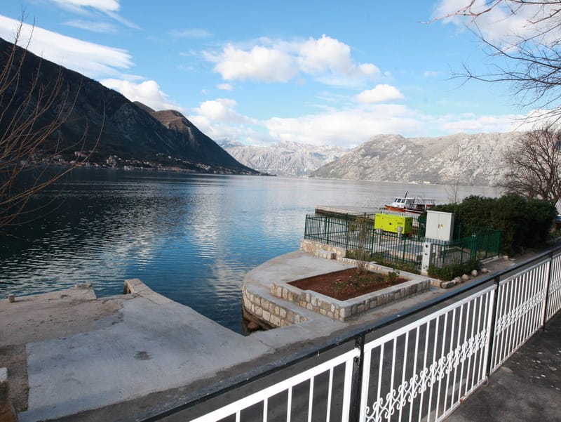 Vue sur la baie de Kotor et le ponton privé de la maison à Dobrota, Monténégro : promenade, montagnes et paysage marin.
