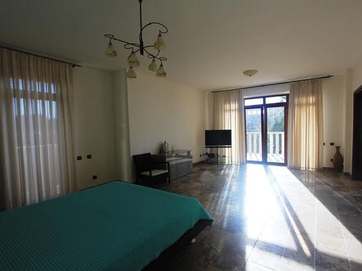 Spacious bedroom in a villa in Petrovac, Montenegro: bed, marble floor, panoramic windows, and access to the terrace.