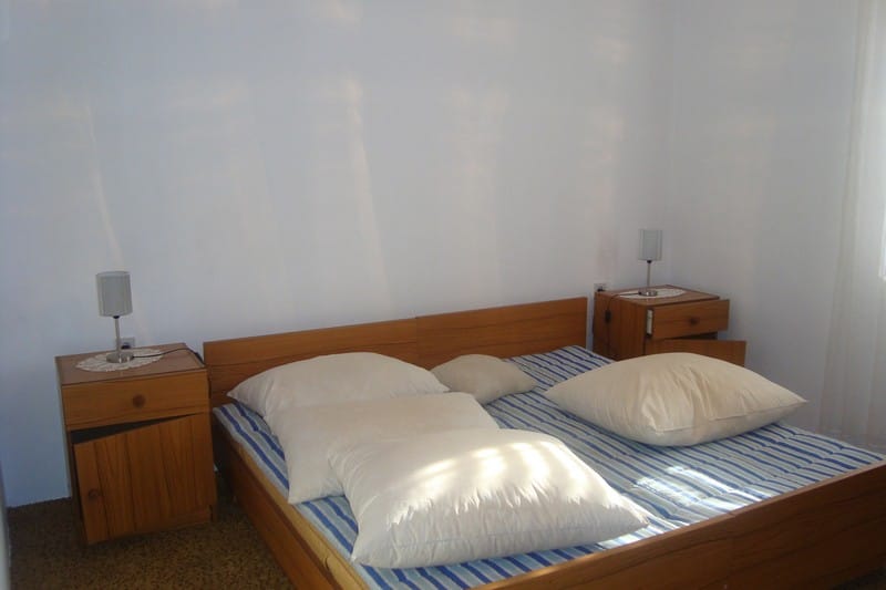 Chambre lumineuse avec lit double et tables de chevet en bois dans une maison à vendre, Dobrota, Monténégro.