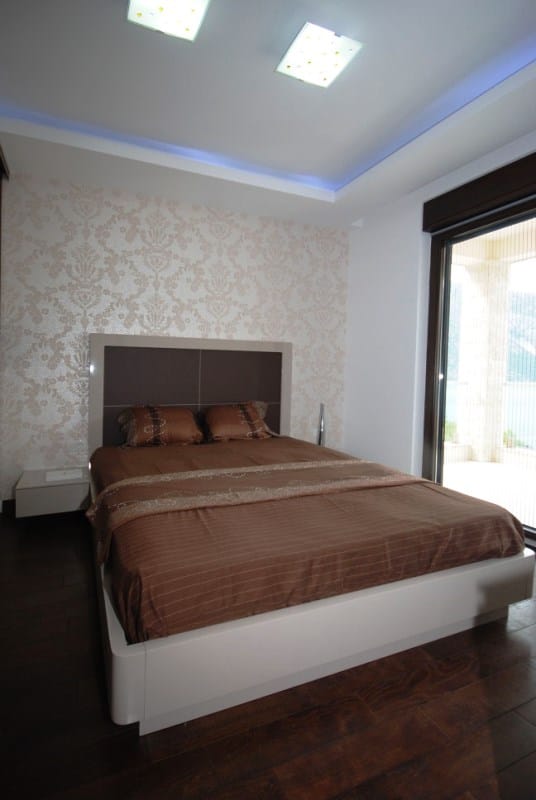 Modernes Schlafzimmer mit Doppelbett in einer Wohnanlage in Kostanica, Montenegro, mit Zugang zur Terrasse und Aussicht.