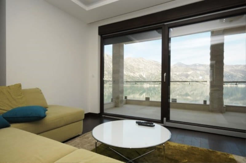 Wohnzimmer mit Panoramablick auf das Meer und die Berge in der Wohnanlage Kostanica, Montenegro: moderne Möbel und Terrasse.