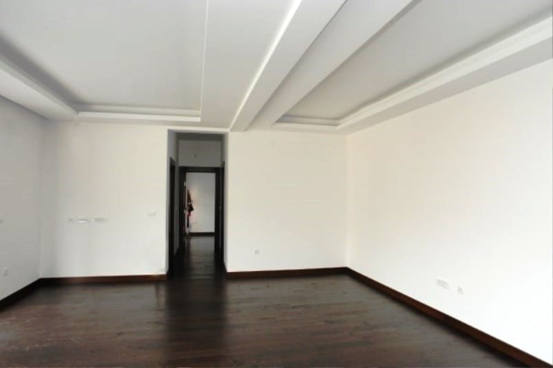 Geräumiges Wohnzimmer mit weißen Wänden und dunklem Parkett in einer Wohnanlage, Kostanica, Montenegro.