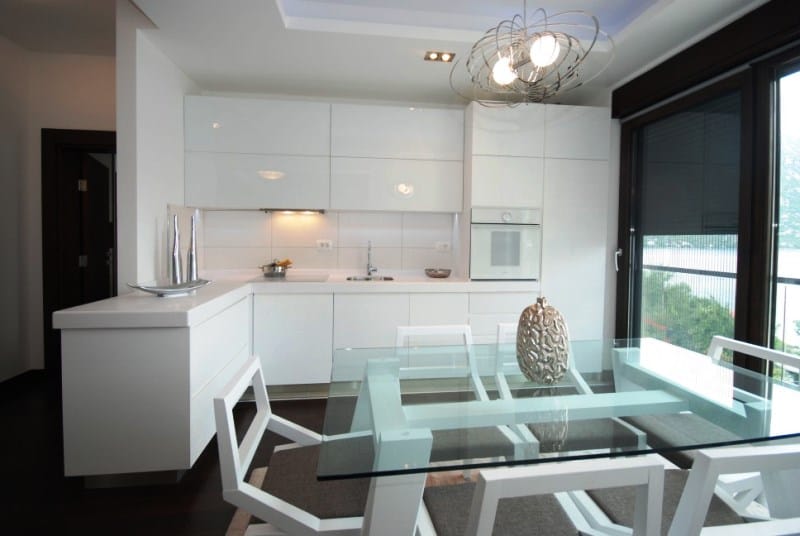 Moderne weiße Küche mit Glastisch in einer Wohnanlage, Kostanica, Montenegro: Meerblick und stilvolles Interieur.