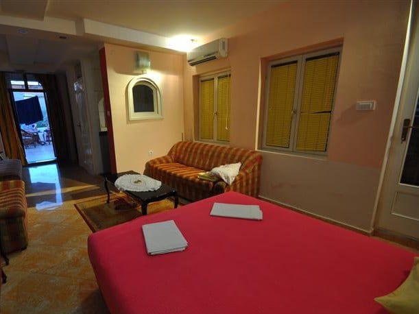 Bedroom interior in a house in Petrovac, Montenegro: double bed, sofa, tiled floor, and access to the terrace.