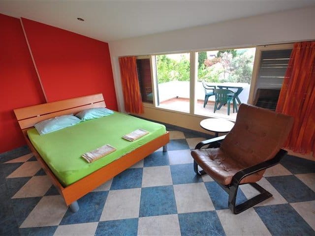 Bedroom in a house in Petrovac, Montenegro: double bed, leather armchair, access to a terrace overlooking the garden.