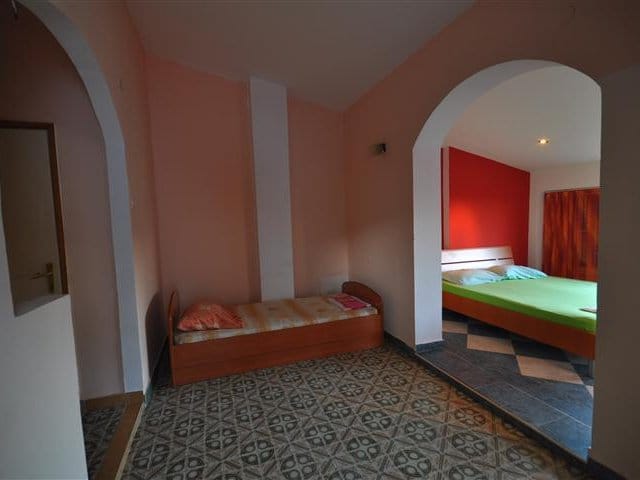 Bedroom in a house in Petrovac, Montenegro: two beds, arched openings, tiled floor, and a bright interior.