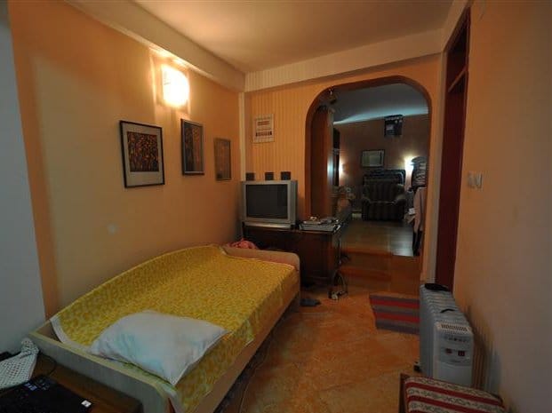 Cozy bedroom with a bed and TV in a house for sale, Petrovac, Montenegro. Interior with an arched passage.