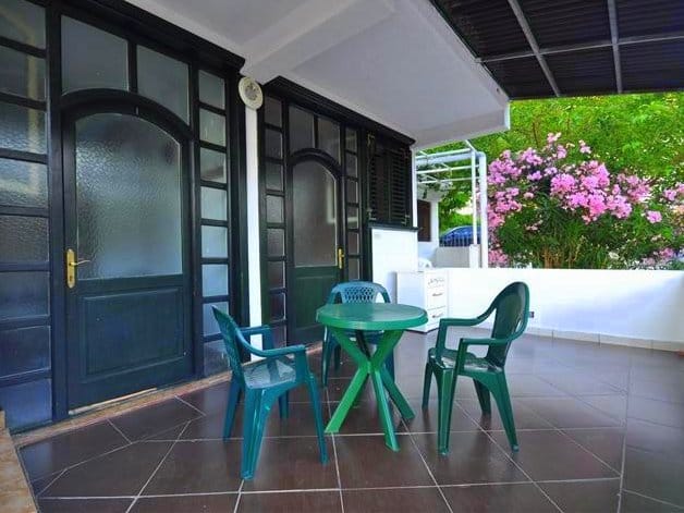 Cozy terrace with plastic furniture and a view of the blooming garden in a house in Petrovac, Montenegro.