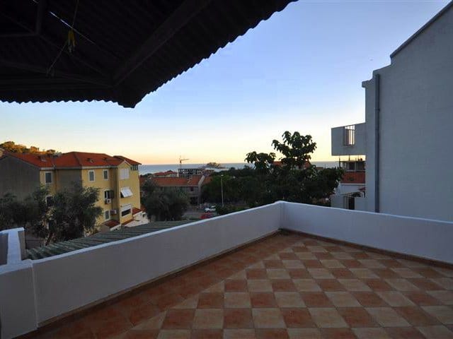 Spacious open terrace with tiled flooring and views of the sea and the city of Petrovac, Montenegro.