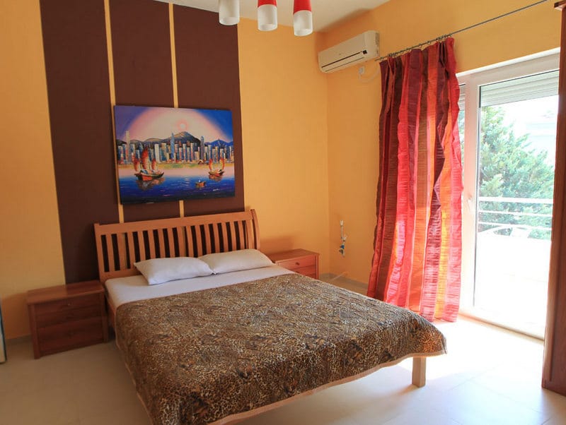 Udobna spavaća soba sa bračnim krevetom u hotelu u Budvi, Crna Gora: svetao enterijer, klima uređaj i izlaz na balkon.