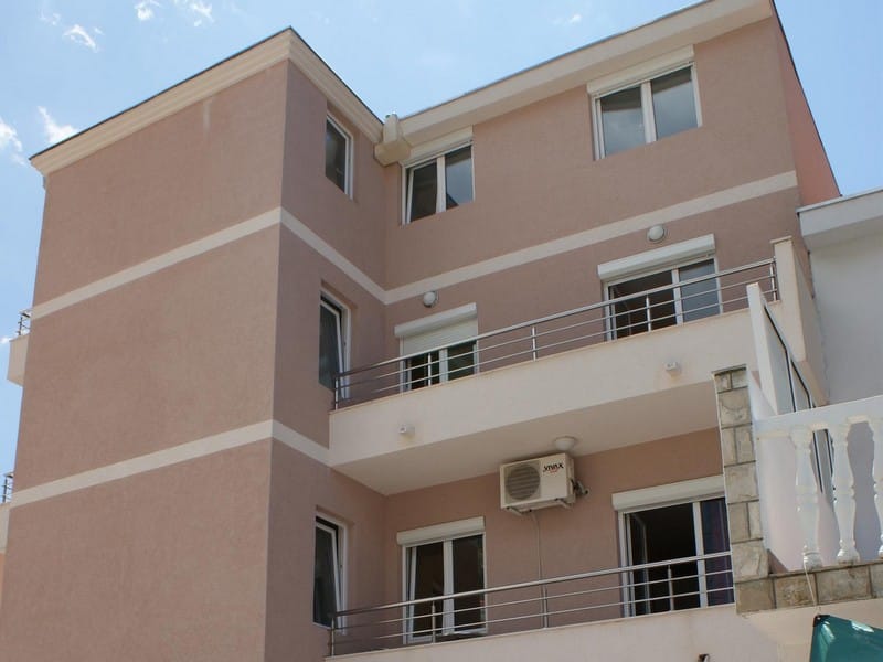 Fasada modernog troetažnog hotela u Budvi, Crna Gora, sa balkonima, panoramskim prozorima i spoljašnjom oblogom zidova.