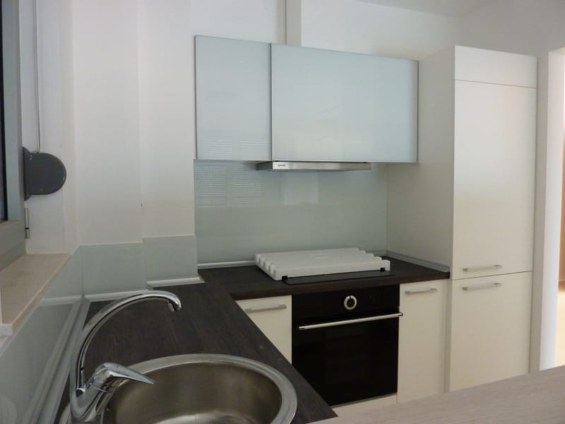 Moderne Küche in einer Wohnung in Pržno, Montenegro: weiße Fronten, dunkle Arbeitsplatte, Einbaugeräte und Spüle.