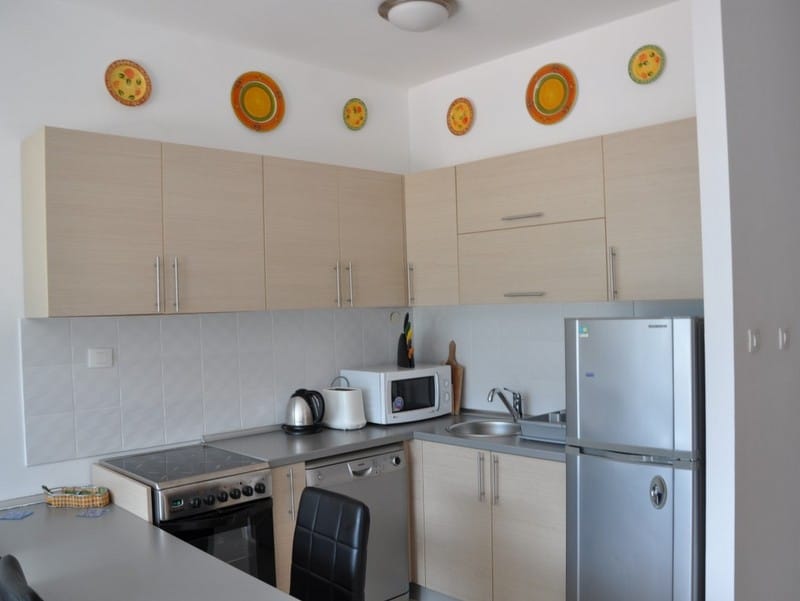 Cuisine lumineuse dans un appartement à Bečići, Monténégro : électroménager encastré, façades beiges et décoration murale.
