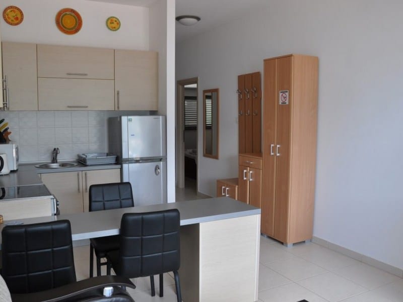 Cuisine-studio avec coin repas et mobilier clair dans un appartement à Bečići, Monténégro. Intérieur moderne avec électroménager.