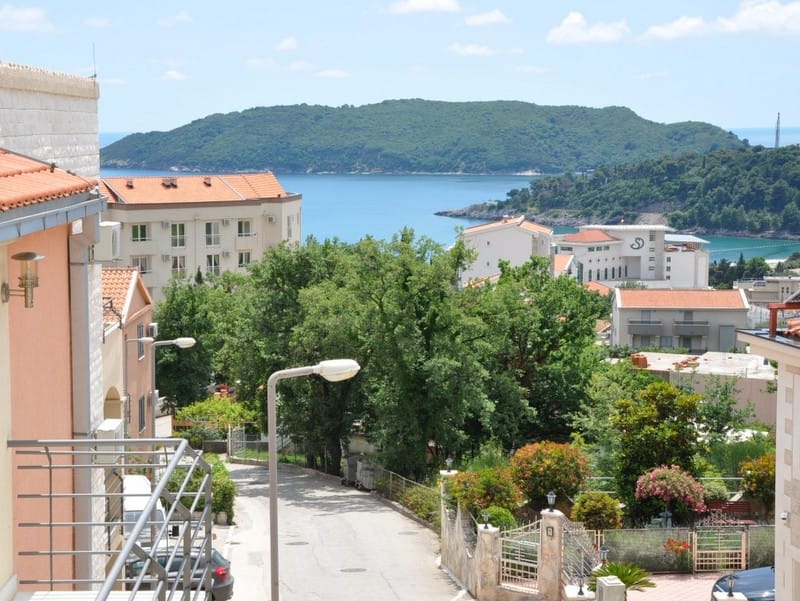Vue depuis le balcon d’un appartement à Bečići, Monténégro : panorama sur la mer, l’île Saint-Nicolas et le quartier verdoyant de la station balnéaire.