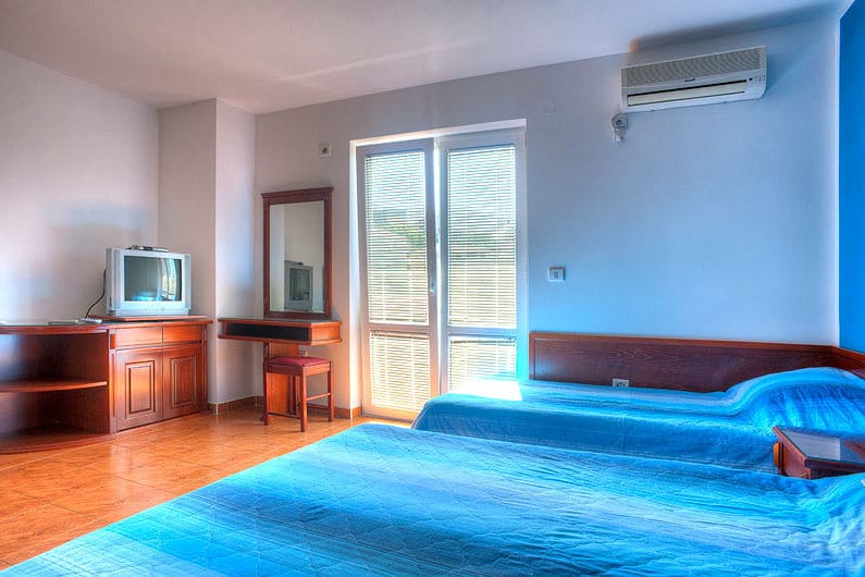 Spavaća soba u hotelu Bečići, Crna Gora: dva kreveta, drveni nameštaj, toaletni sto sa ogledalom i klima uređaj.
