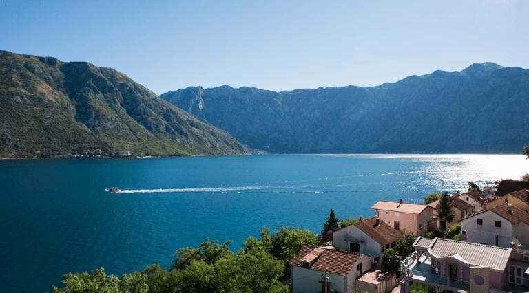 Panoramablick auf die Bucht von Kotor und die Berge vom Haus in Stoliv, Montenegro: Meer, Motorboot und Küstengebäude.