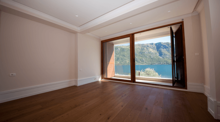 Helles Wohnzimmer mit Holzboden und Panoramablick auf das Meer und die Berge in einem Haus, Stoliv, Montenegro.