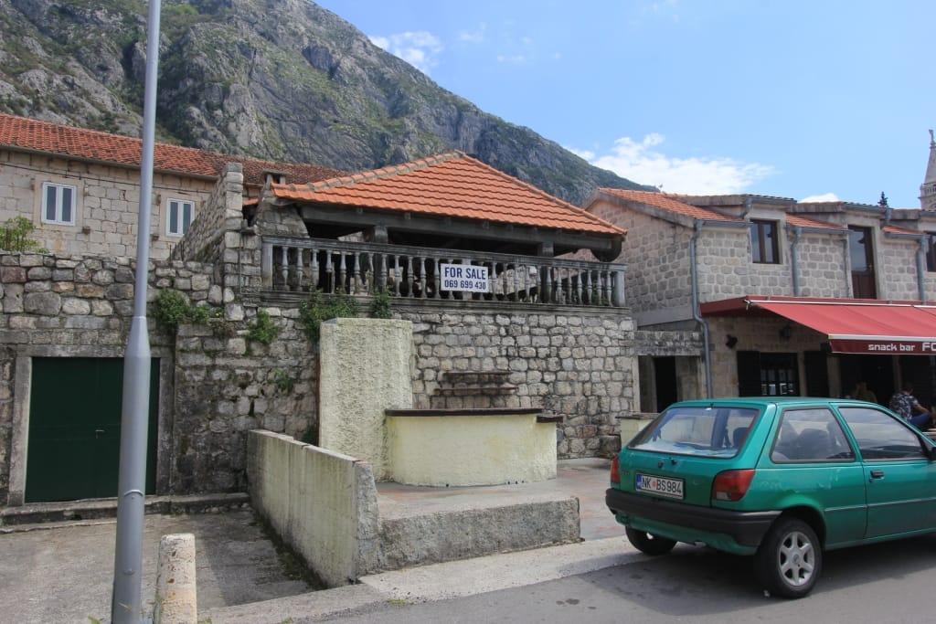 Maison en pierre à vendre à Dobrota, Monténégro : architecture traditionnelle avec terrasse au pied des montagnes.