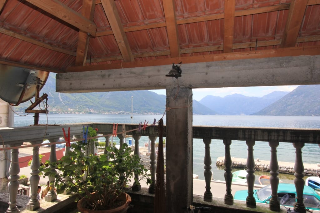 Vue depuis le balcon sur la baie de Kotor et les montagnes à Dobrota, Monténégro : terrasse avec balustrade et toit en tuiles.