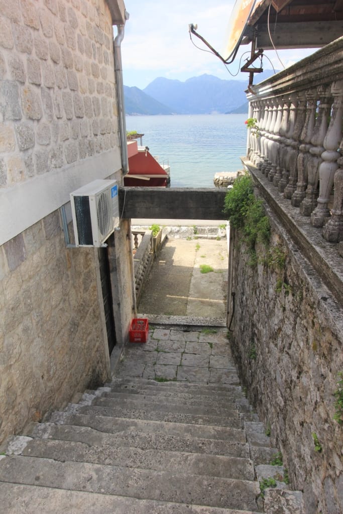 Escalier en pierre vers la mer près de la maison à Dobrota, Monténégro : vue sur la baie de Kotor et les montagnes entre les anciens murs.