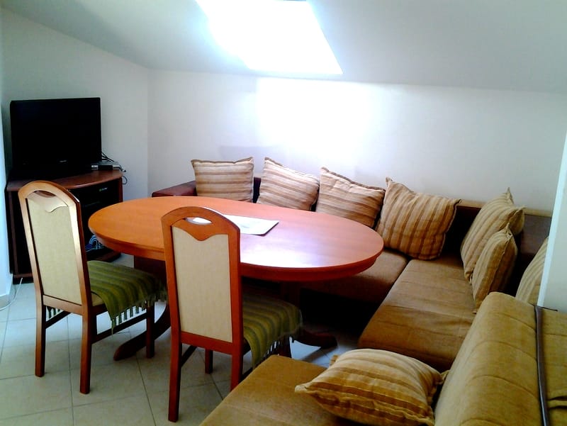 Living room in an apartment in Bar, Montenegro: dining area with an oval table, a soft corner sofa, and a skylight.