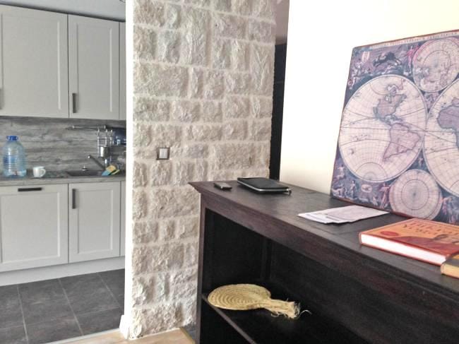 Innenraum einer Wohnung in Dobrota, Montenegro: Küche mit hellen Fronten und Akzentwand aus Naturstein.