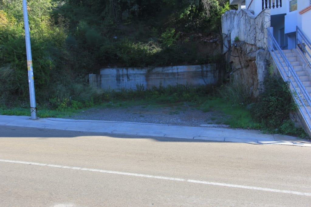 Building plot in Petrovac, Montenegro: level area by the road with a retaining wall and stairs.