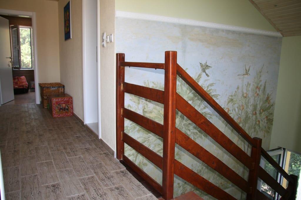 Escalier en bois et mur peint à l’intérieur d’un appartement à Radovici, Monténégro : vue sur le couloir et le carrelage imitation bois.