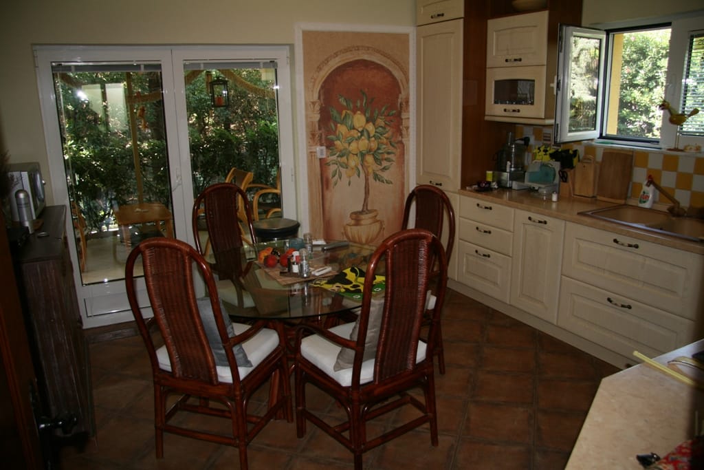 Cuisine avec coin repas et mobilier en rotin dans l’appartement, Radovići, Monténégro : vue sur la terrasse et décoration aux citrons.
