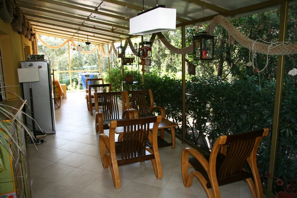 Terrasse couverte chaleureuse avec fauteuils en bois dans l’appartement, Radovići, Monténégro : vue sur le jardin et décoration élégante.