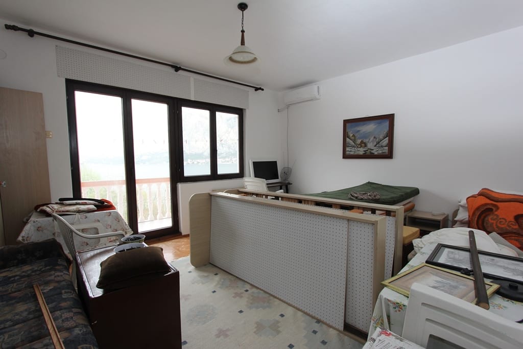Salon z wyjściem na balkon i widokiem na morze w domu, Prčanj, Czarnogóra: jasny pokój z meblami i klimatyzacją.