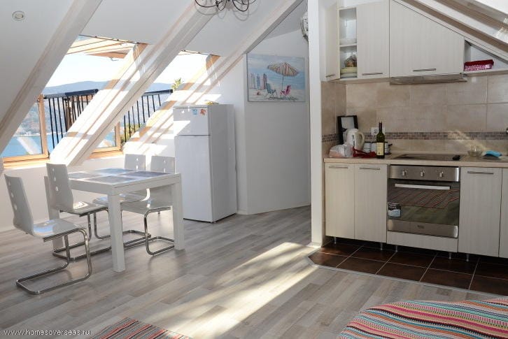 Küche mit Essbereich in einer Dachgeschosswohnung in Herceg Novi, Montenegro: helle Möbel, Meerblick und Panoramafenster.