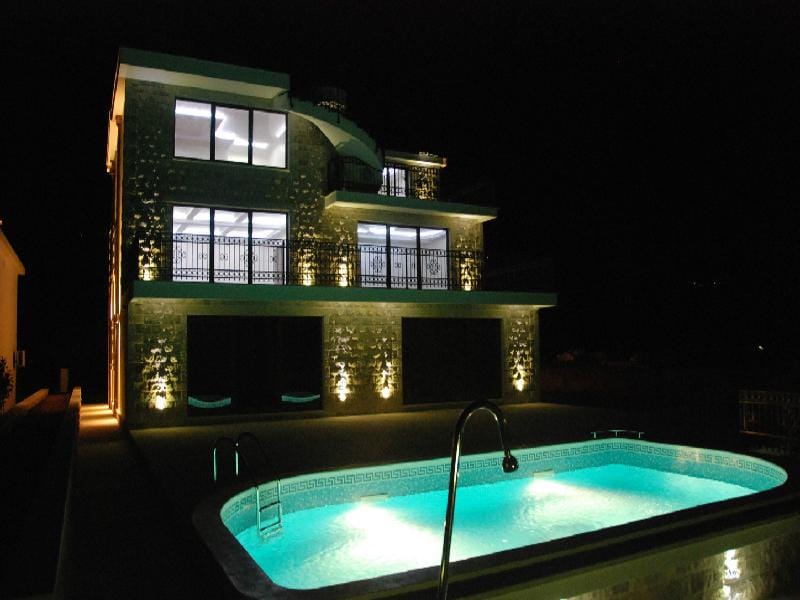 Villa de trois étages avec piscine et éclairage nocturne de la façade à Herceg Novi, Monténégro. Maison moderne avec terrasses.