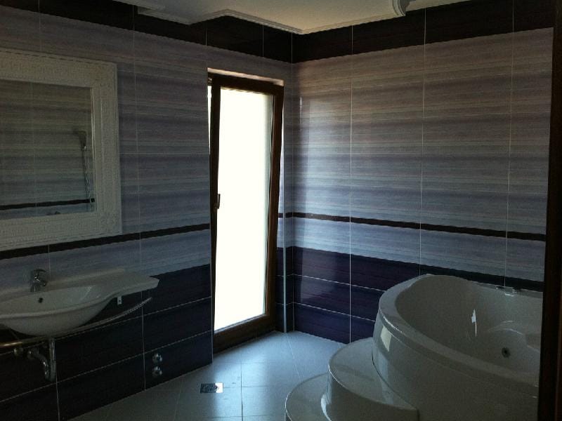 Salle de bains avec baignoire d’angle et miroir dans une villa à Herceg Novi, Monténégro : finition moderne en carrelage.