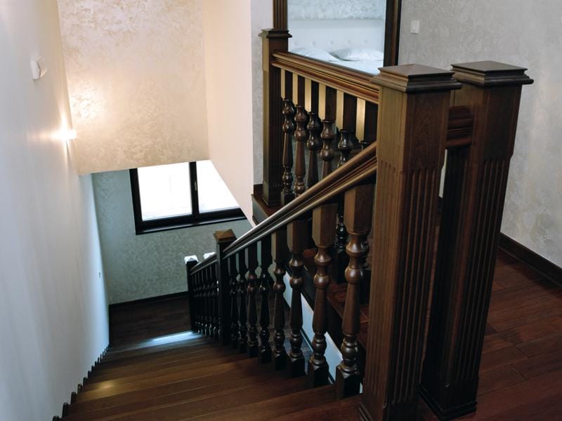 Escalier en bois avec rampe sculptée à l’intérieur d’une villa à Herceg Novi, Monténégro, avec vue sur le deuxième étage.