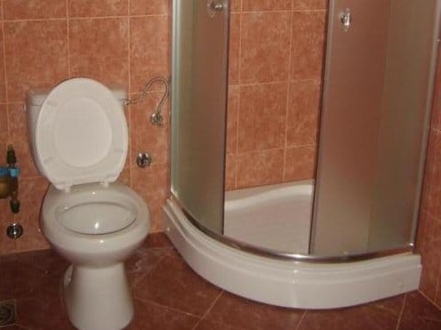 Kupatilo u stanu u Sutomoru, Crna Gora: tuš kabina i sanitarije na pozadini terakota pločica.