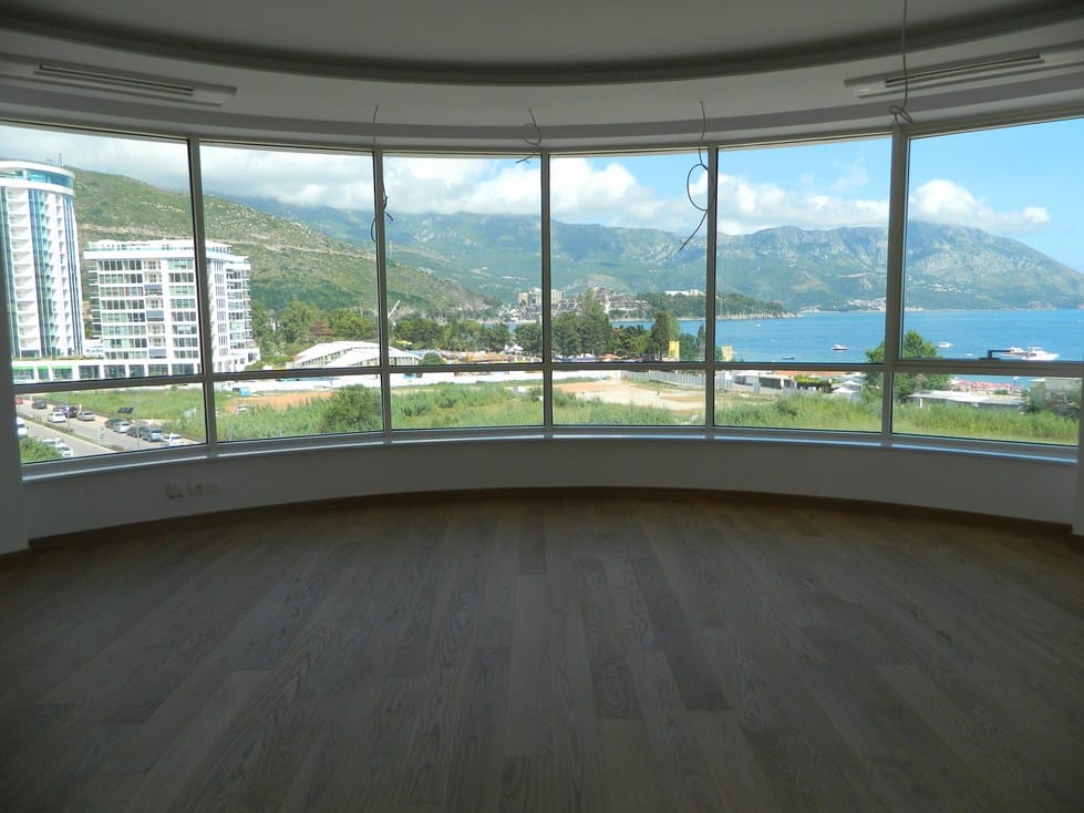 Panoramski pogled na more i planine iz dnevne sobe novog stana u Budvi, Crna Gora, sa kvalitetnim parketnim podom.