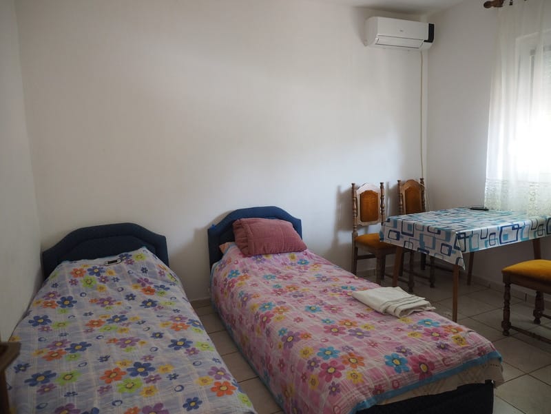 Schlafzimmer mit zwei Betten, Esstisch und Klimaanlage in einem Haus zum Verkauf, Stadt Bar, Montenegro.