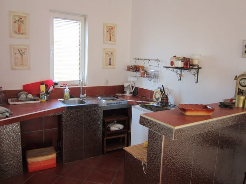 Cuisine dans une maison à Utjeha, Monténégro : carrelage couleur terracotta, bar et espace compact pour la préparation des repas.