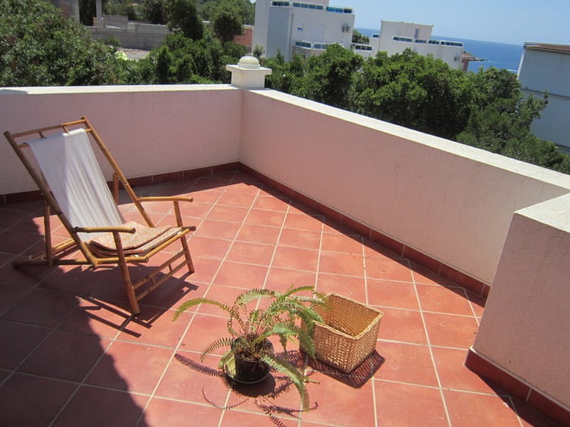 Terrasse avec transat et vue sur la mer dans une maison à Utjeha, Monténégro : sol carrelé, verdure et coin détente cosy.