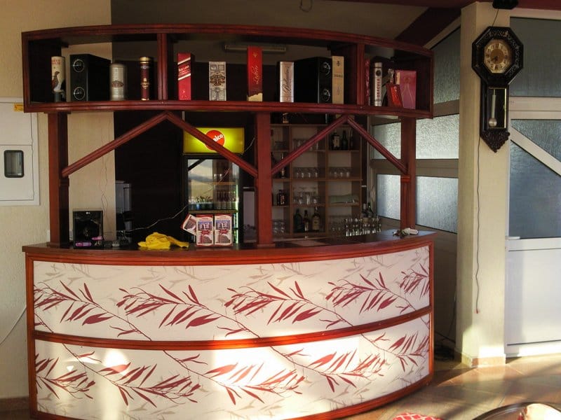 Wooden bar counter with drink shelves in a hotel interior in Bar, Montenegro.