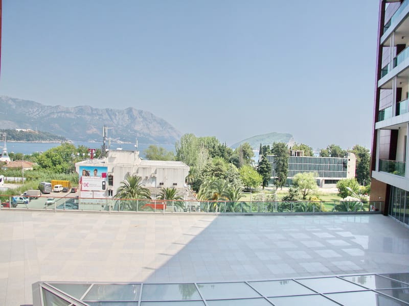 Pogled sa terase poslovnog centra u Budvi, Crna Gora: panorama mora, planina i gradske infrastrukture.