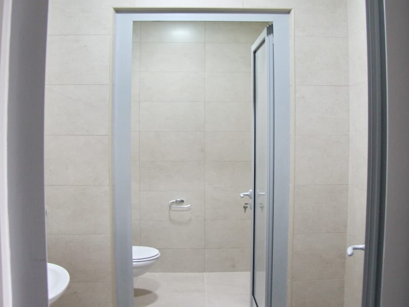 Savremeno kupatilo u kancelariji u Budvi, Crna Gora: svetle pločice, kvalitetna sanitarija i stilizovana završna obrada.