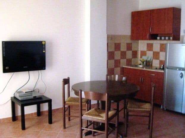 Kitchen-dining room in a villa apartment in Budva, Montenegro: dining area, wooden furniture set, and TV area.