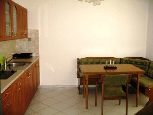 Kitchen with wooden cabinetry and dining area in a villa, Budva, Montenegro. Cozy dining room with a soft seating area.
