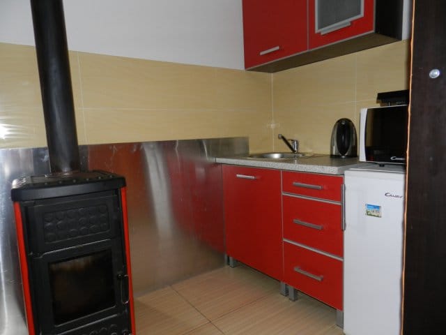 Küche mit roter Einbauküche und Holzofen in einem Haus zum Verkauf, Stadt Bar, Montenegro.