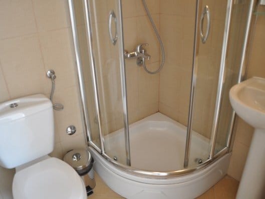 Kupatilo u stanu u Bečićima, Crna Gora: tuš kabina, bela sanitarija i bež pločice na zidovima.